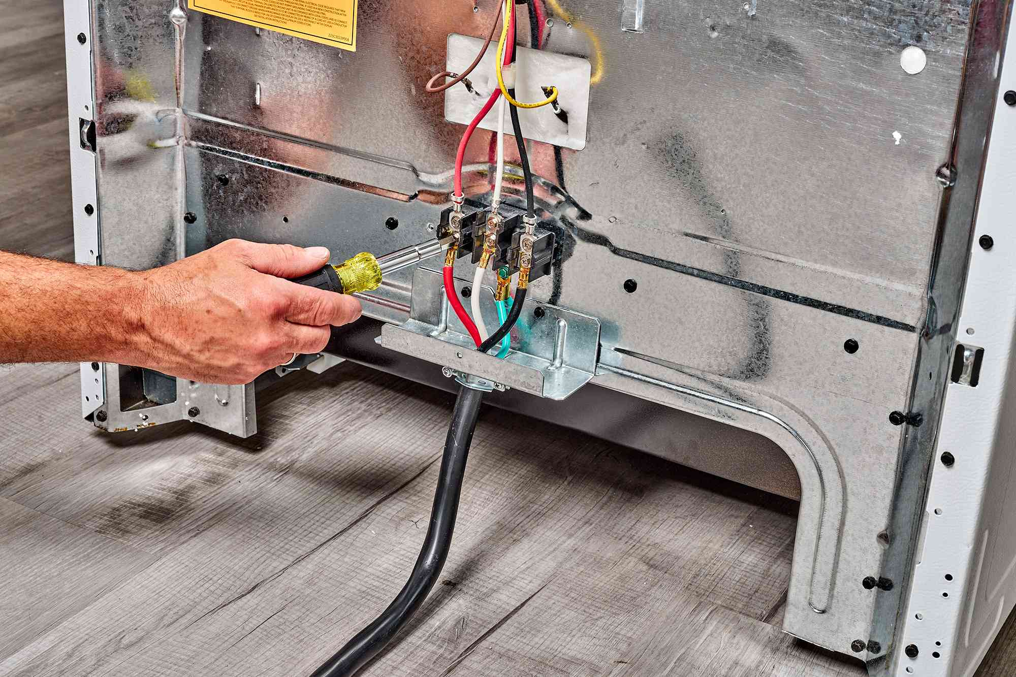 Electrician examining the wiring connections at the back of a Frigidaire oven